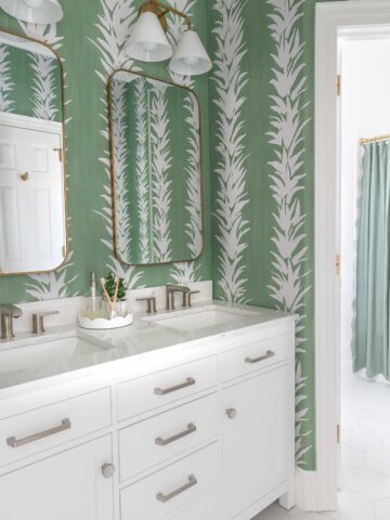 White bathroom vanity in bathroom with green wallpaper